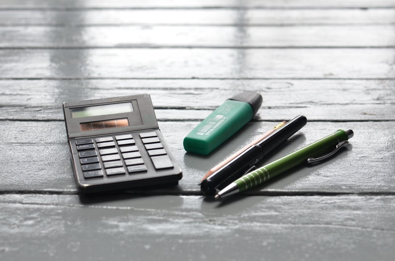 Calculator and pens on wooden desk